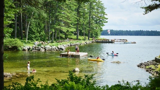 人们在湖边划皮划艇、游泳、在水中玩耍。